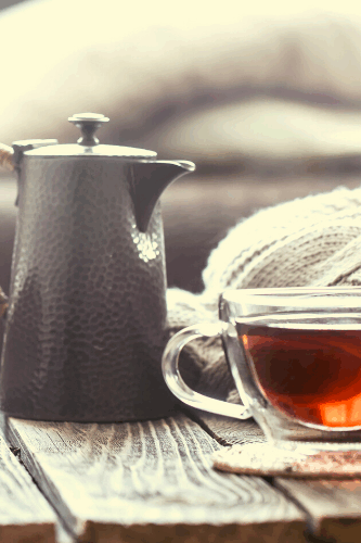 Teekanne mit Teetasse aus Glas auf Holztisch