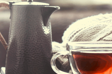 Teekanne mit Teetasse aus Glas auf Holztisch