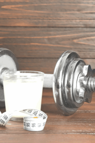 Hantel mit Isotonischem getr&auml;nk und Messband im Vordergrund