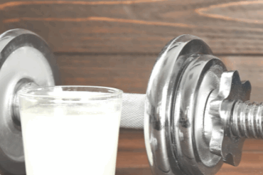 Hantel mit Isotonischem getränk und Messband im Vordergrund